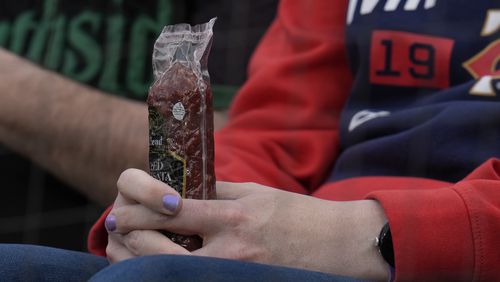 A Minnesota Twins fan holds a sausage before a baseball game against the Chicago White Sox, Monday, April 29, 2024, in Chicago. The Twins recently began passing around summer sausages in the dugout. (AP Photo/Erin Hooley)