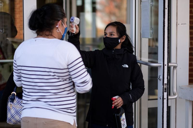 Cynthia Torrez pre-screens a patient for COVID-19 symptoms and gives her hand sanitizer before allowing her into Good Samaritan Health Center in Northwest Atlanta.  (Ben Gray for the AJC)