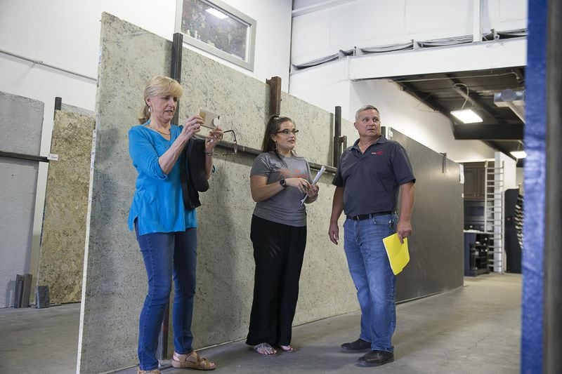 Mega Granite & Marble employee Hannah Kupfer (center) shows Linda Smith (left) and her son-in-law Chip Smith (right) a countertop slab on the company sales floor in Newnan. (Alyssa Pointer/alyssa.pointer@ajc.com)