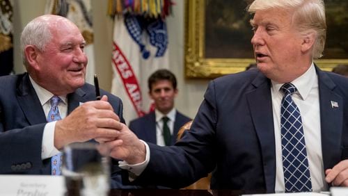 President Donald Trump hands a pen to Agriculture Secretary Sonny Perdue after signing an executive order during farmers' roundtable in the Roosevelt Room of the White House in Washington, Tuesday, April 25, 2017. (AP Photo/Andrew Harnik)