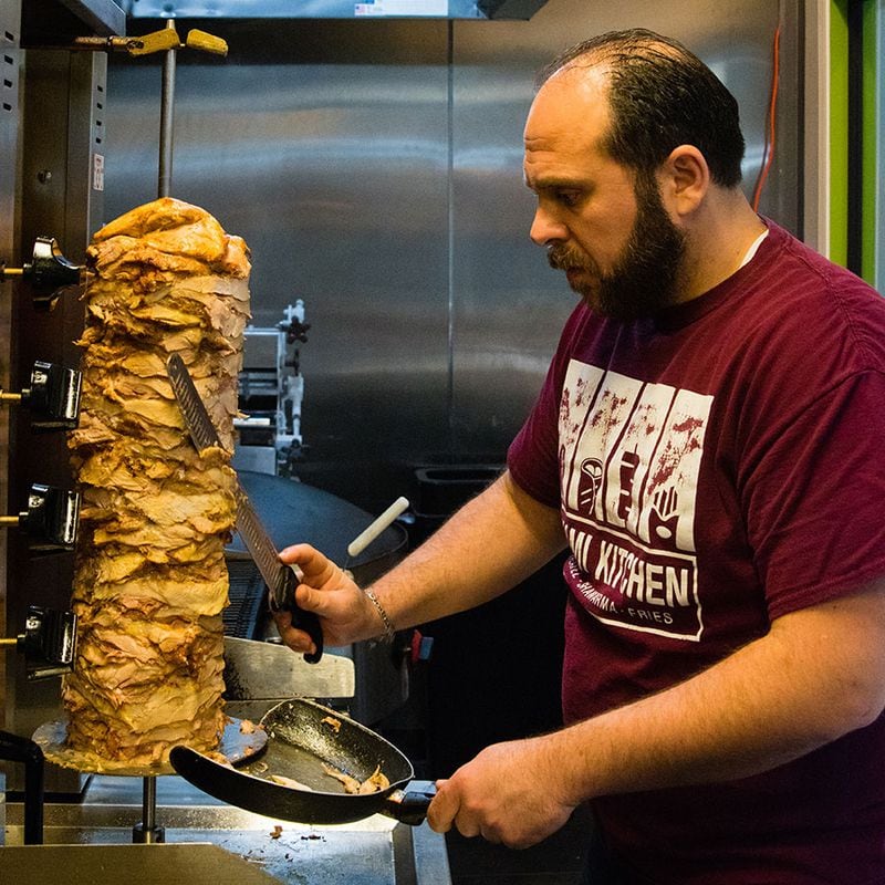 Chef Aboud Alhalabi carves chicken shawarma from the roasting spit. CONTRIBUTED BY HENRI HOLLIS