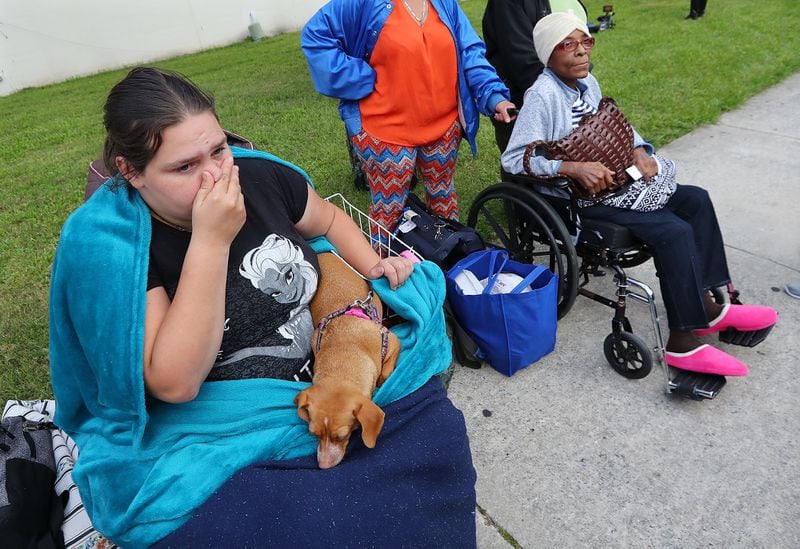 Crystal Russell, 22, with her dog Rory, and Frankie Richardson, 70, join hundreds being evacuated from Savannah Saturday. Officials are expecting 1,500 to 3,000 without transportation to leave by buses that are being provided. Curtis Compton/ccompton@ajc.com