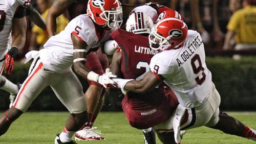Bulldogs defensive back Damian Swann (from left) tries to bottle up Gamecocks running back Marcus Lattimore with the help of linebacker Alec Ogletree.