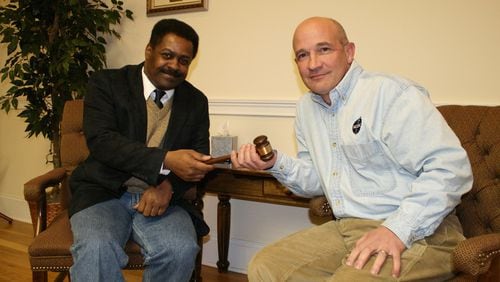 February 2010: Dr. Carlo Musso (right), then-outgoing chairman of the Housing Authority of Clayton County and the proprietor of a jail medical services company, hands the gavel to his successor, James Searcy. Musso recently purchased a former Georgia state prison for $50,000 -- half its appraised value -- in what one competing business believes is a sweetheart deal with the state Department of Corrections.