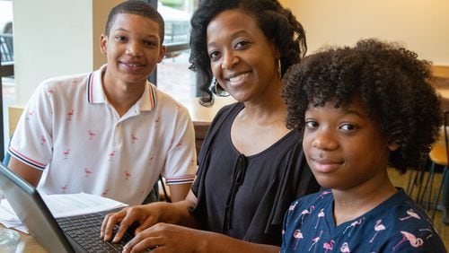 Athara Toussaint (center), searches for her grades online while having breakfast with her sons Dallas (left, age 17) and Julian (14).