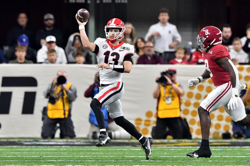 Georgia Bulldogs quarterback Stetson Bennett (13) attempts a pass against the pressure from Alabama Crimson Tide linebacker Christian Harris (8) during the first quarter at the 2022 College Football Playoff National Championship at Lucas Oil Stadium in Indianapolis on Monday, January 10, 2022.   Hyosub Shin / Hyosub.Shin@ajc.com 
