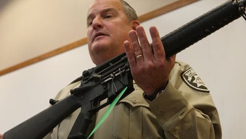 Former Cherokee County Sheriff Roger Garrison, displaying an AR-15 taken from a suspect's home. (Bob Andres/bob.andres@ajc.com)