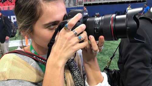 UGA intern Chamberlain Smith shoots a photo of Georgia coach Kirby Smart coming onto the field at Mercedes-Benz Stadium on Saturday. It's her first game back since she was injured in a sideline collision at Auburn on Nov. 16. (Chip Towers/ctowers@ajc.com)