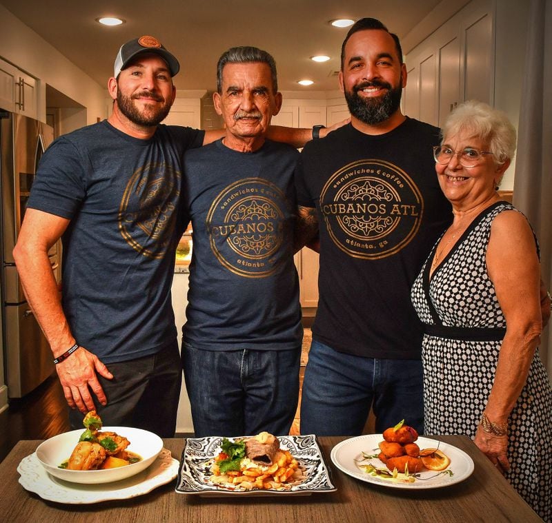 From left: Alex Valdivia (best friend of Ozzy Llanes), Osvaldo Llanes (father), Ozzy Llanes (son) and Amarilys Llanes (mother) are shown with several Cuban dishes: (from left) Fricassee de Pollo con Papas (Chicken Fricassee with Potatoes), Palomilla Steak and French Fries, and Serrano Ham and Bechamel Croquetas. The photos were taken at the home of Ozzy Llanes, owner of Cubanos ATL. Food styling by Ozzy Llanes and Alex Valdivia / Chris Hunt /For The AJC