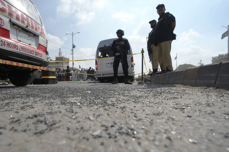 Police officers stand guard at the site of suicide attack in Karachi, Pakistan, Friday, April 20, 2024. Five Japanese nationals traveling in a van narrowly escaped a suicide attack when a suicide bomber detonated his explosive-laden vest near their vehicle in Pakistan's port city of Karachi on Friday, wounding three passers-by, police said. (AP Photo/Fareed Khan)