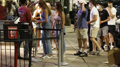 A few weeks after University of Georgia classes resumed this fall. a doorman checked customers' temperatures as they waited to enter a bar in downtown Athens.  (Joshua L. Jones/Athens Banner-Herald via AP)