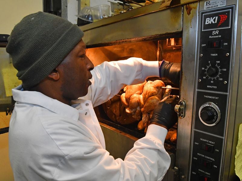 Diamond Mardell gets the whole chicken roasters going in the morning at Shield's Meat Market. Chris Hunt for The Atlanta Journal-Constitution