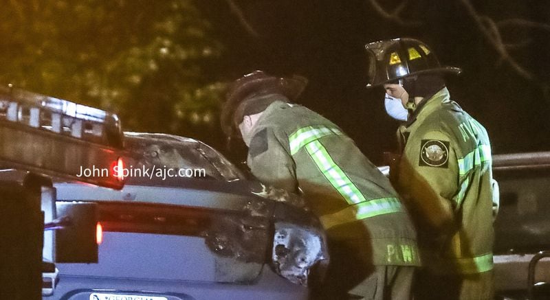 Firefighters work to remove a shooting victim from a burned car on Center Hill Avenue in northwest Atlanta.