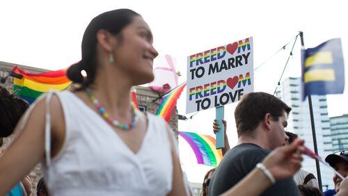 Laila Flores, left, celebrates as Chip O' Kelly, partially seen, holds a sign in downtown Atlanta following the Supreme Court's ruling that made gay marriage constitutional across the nation, Friday, June 26, 2015. (BRANDEN CAMP/AJC FILE PHOTO)