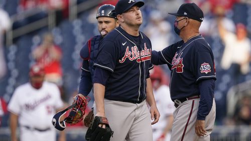 Atlanta Braves relief pitcher Tyler Matzek walks off the field after being relieved by Atlanta Braves manager Brian Snitker, right, in the seventh inning of an opening day baseball game against the Washington Nationals at Nationals Park, Tuesday, April 6, 2021, in Washington. (AP Photo/Alex Brandon)