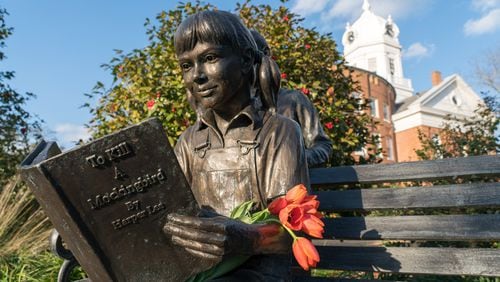 Flowers left on a statue in Monroeville, Ala., the hometown of Harper Lee, on the day of her death, Feb. 19, 2016. Lee’s death at 89 struck a chord around the world, but nowhere did it resonate as deeply as in the town where she grew up and set her masterpiece, “To Kill a Mockingbird.” Schools in Biloxi, Mississippi banned the book this week. (Jeff Haller/The New York Times)