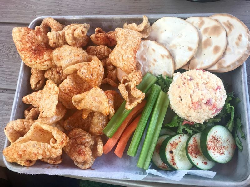 An order of the House Pimento Cheese with carrot and celery sticks, cucumber slices dusted with powdered Sriracha and pork rinds from the Nest in Kennesaw. LIGAYA FIGUERAS / LFIGUERAS@AJC.COM