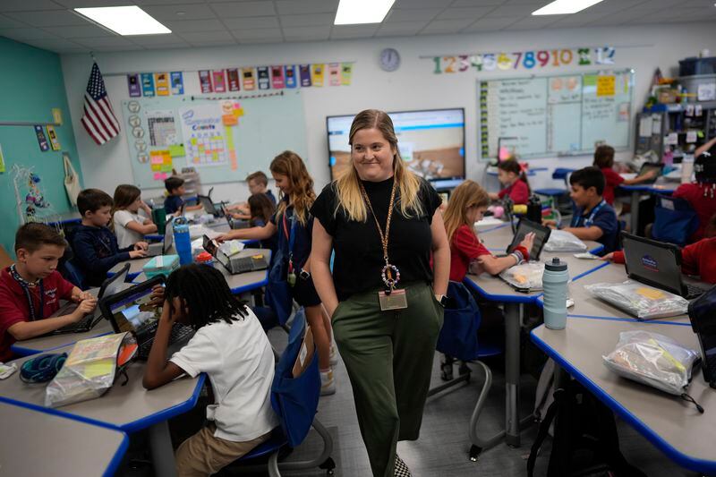 Third grade teacher Megan Foster walks through her classroom as students take a break from a reading lesson to explore a computer animation of the planet Mars, at A.D. Henderson School in Boca Raton, Fla., Tuesday, April 16, 2024. When teachers at the K-8 public school, one of the top-performing schools in Florida, are asked how they succeed, one answer is universal: They have autonomy. (AP Photo/Rebecca Blackwell)