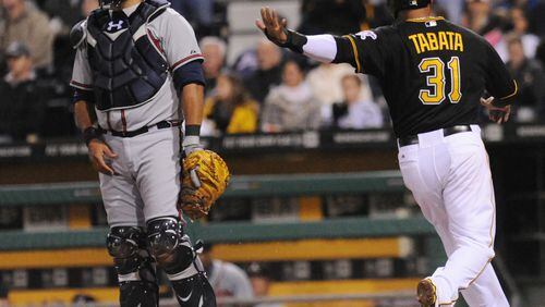 Braves catcher, Gerald Laird waits on the throw to the plate as Pittsburgh Pirate Jose Tabata (right) scores in the 3-run fifth inning iof a baseball game at PNC Park Friday in Pittsburgh.