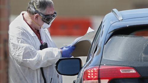 A worker, wearing protective gear, checks in a person at a mobile testing site for COVID-19 in Oklahoma City, Thursday March 26, 2020. (AP Photo/Sue Ogrocki)