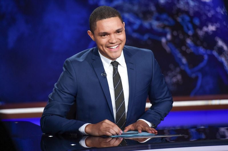 FILE - In this Sept. 29, 2015 file photo, Trevor Noah appears on set during a taping of "The Daily Show with Trevor Noah" in New York. Noah is bringing a sideshow with him to the Republican convention. The "Daily Show" plans an interactive exhibit in Cleveland next week, with a "Run For the Border" avatar race, a "Yuuuge Wall" for artists to paint on and a replica of show's desk as selfie bait. (Photo by Evan Agostini/Invision/AP, File)