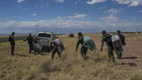 U.S. Border Patrol agents carry bales of marijuana they found along the highway near Ryan, Texas, about 20 miles from the US-Mexico border, Tuesday, March 28, 2017. One agent said "They (the smugglers) just leave it and come back another day. It's going to be sad when they come back for it." Drug interdiction is a core mission for the Border Patrol. (AP Photo/Rodrigo Abd)