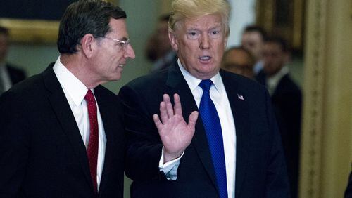 President Donald Trump escorted by Sen. John Barrasso, R-Wyo., chairman of the Senate Republican Policy Committee, arrives at the Capitol to meet with GOP lawmakers about moving his agenda and passing the Republican tax bill, in Washington, Tuesday, Nov. 28, 2017. ( AP Photo/Jose Luis Magana)