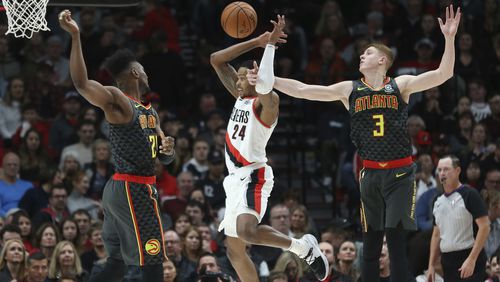Portland Trail Blazers guard Kent Bazemore (center) is fouled by Atlanta Hawks guard Kevin Huerter (right) as forward Bruno Fernando defends during the first half Sunday, Nov. 10, 2019, in Portland, Ore.