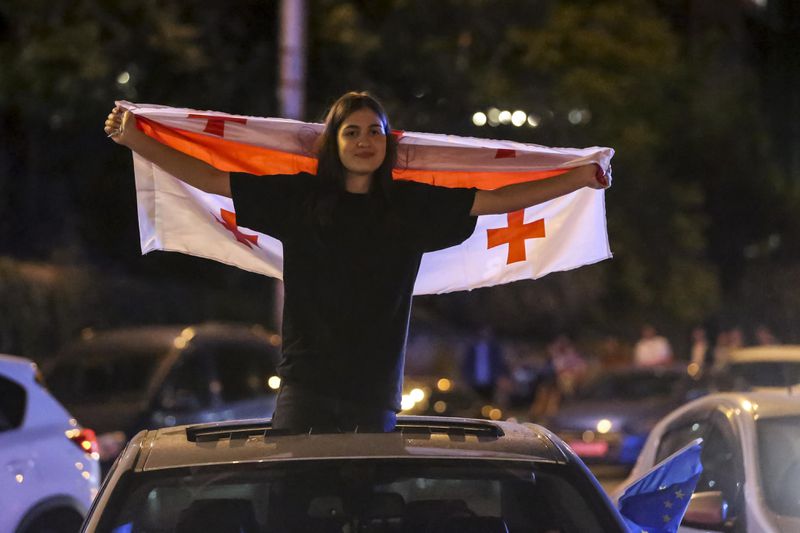 A demonstrator holds a Georgian national flag during an opposition protest against "the Russian law" in the center of Tbilisi, Georgia, on Thursday, May 2, 2024. The parliament of Georgia has cancelled its plenary session following massive protests against a proposed law that critics fear will stifle media freedom and endanger the country's bid for membership in the European Union. (AP Photo/Zurab Tsertsvadze)