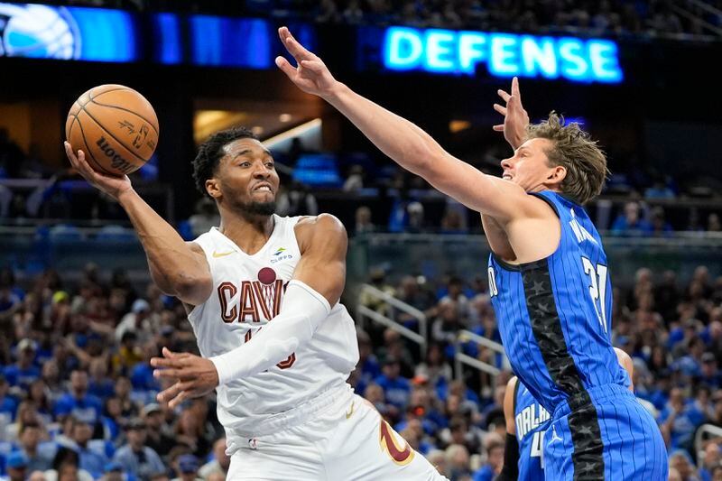 Cleveland Cavaliers guard Donovan Mitchell, left, passes the ball around Orlando Magic center Moritz Wagner during the first half of Game 4 of an NBA basketball first-round playoff series, Saturday, April 27, 2024, in Orlando, Fla. (AP Photo/John Raoux)