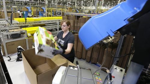 An Amazon worker places an item in a box for shipment during a media tour of a fulfillment center in Washington. (AP Photo/Ted S. Warren, File)