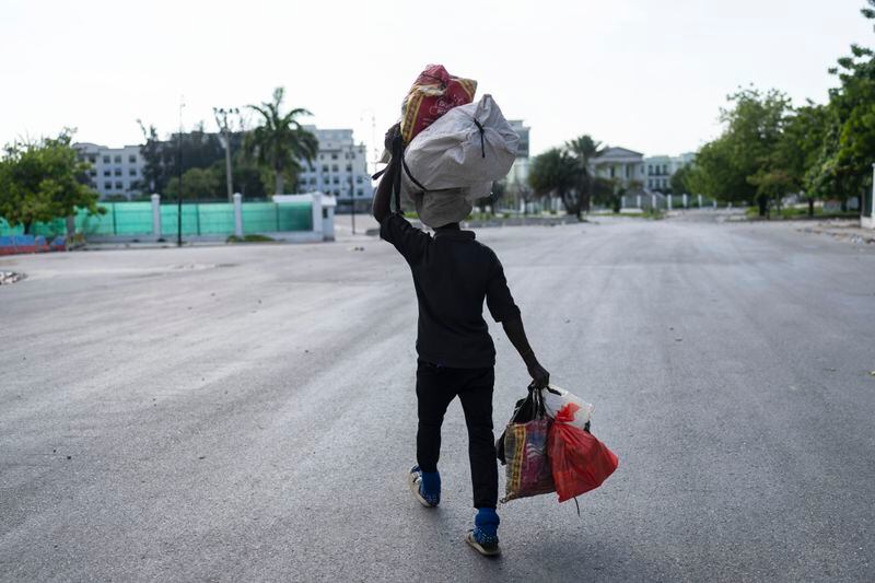 A person hauling bags walks past the National Palace in Port-au-Prince, Haiti, Tuesday, April 23, 2024. (AP Photo/Ramon Esp