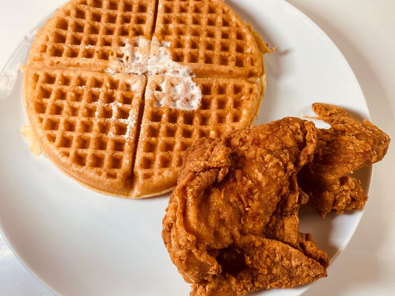 The signature dish at Johnny’s Chicken and Waffles can be ordered with a choice of protein, a plain or red velvet waffle and several sauces. (Bob Townsend for The Atlanta Journal-Constitution)