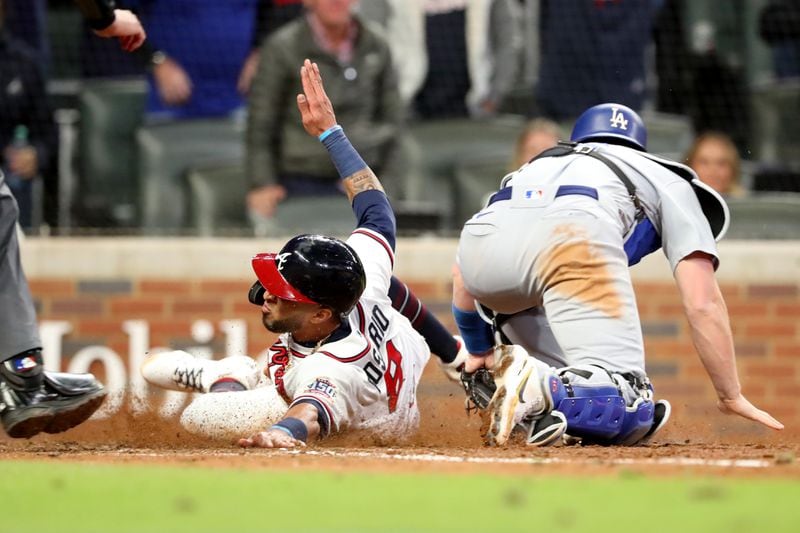 Braves leftfielder Eddie Rosario slides into home plate to score a run ahead of the tag by Los Angeles Dodgers catcher Will Smith during the eighth inning of Game 2 of the NLCS Sunday, Oct. 17, 2021, at Truist Park in Atlanta. (Curtis Compton / curtis.compton@ajc.com)