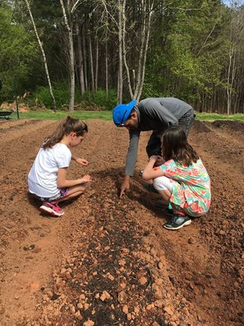 Gardener Abu Talib, a Rohingyan refugee from Myanmar, teaches Scarlett Vaughan and her friend how to plant lettuce seeds in the Vaughans’ Lilburn farm. CONTRIBUTED
