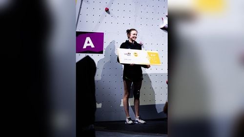 Speed rock climber Emma Hunt smiles with ticket after qualifying for 2024 Paris Olympics at the world championships in Bern, Switzerland.