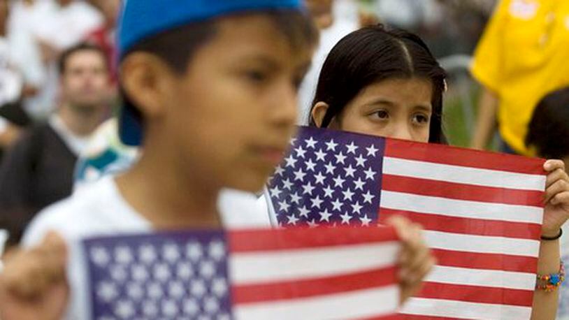In 2010, Jason Rosales, 10, and his sister Jessica Rosales, 8, of Norcross, hold American flags during a march in support of immigration reform in downtown Atlanta.