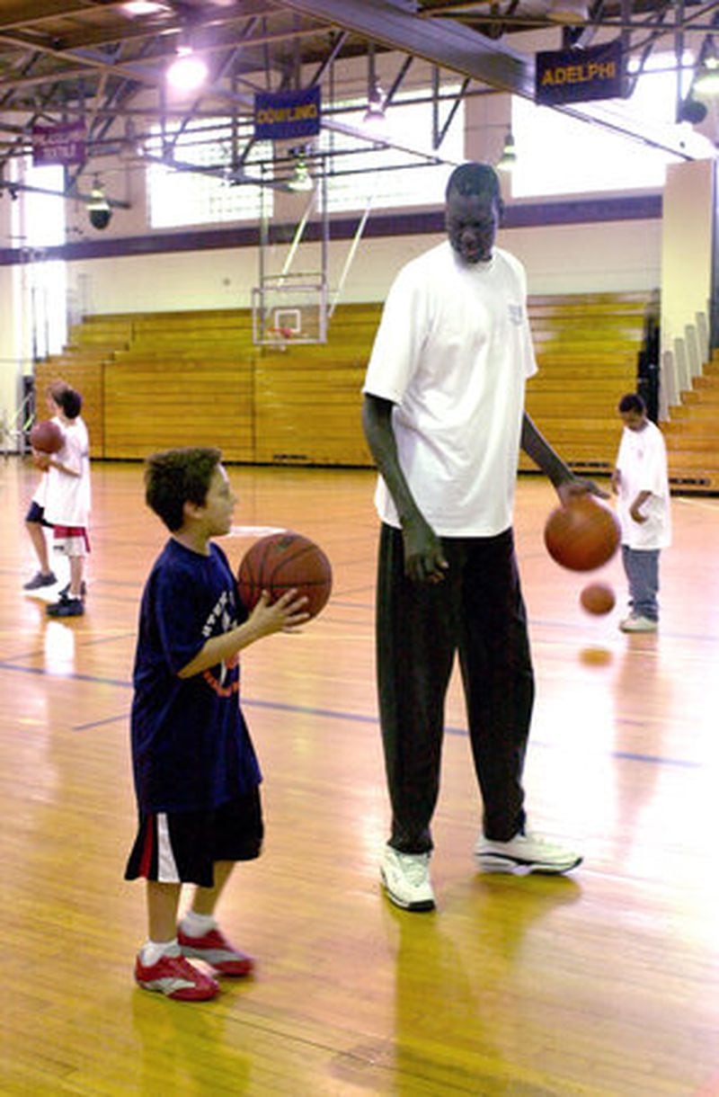 Former NBA star Manute Bol works with a young boy at a basketball clinic Bol was giving in Bridgeport, Conn., June 15, 2002. (AP photo)