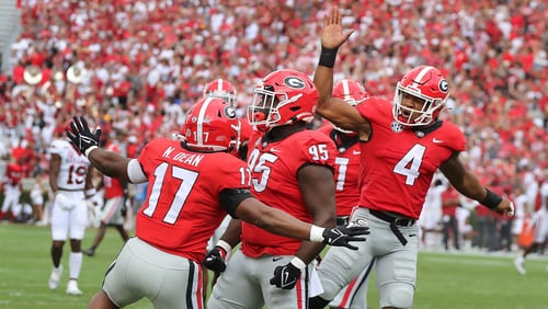 Georgia defenders Nakobe Dean (from left), Devonte Wyatt, and Nolan Smith celebrate after Wyatt sacked Arkansas quarterback KJ Jefferson during the first quarter in a 37-0 shutout over Arkansas on Saturday, Oct. 2, 2021, in Athens.  Curtis Compton / Curtis.Compton@ajc.com