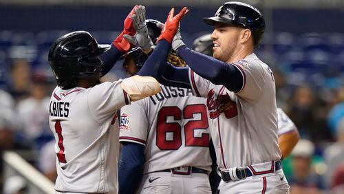 Freddie Freeman celebrates with Ozzie Albies (1) and Touki Toussaint (62) after his home run in the fourth inning of Monday's Braves-Marlins game in Miami.