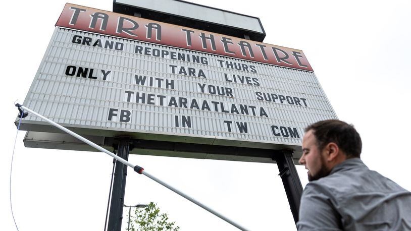 Christopher Escobar, new owner of the Tara Theatre, puts up the “Grand Reopening” sign outside the Tara in Atlanta on Monday, May 22, 2023. Tara Theatre will reopen on Thursday six months after Regal Cinema abruptly shut it down. (Arvin Temkar / arvin.temkar@ajc.com)