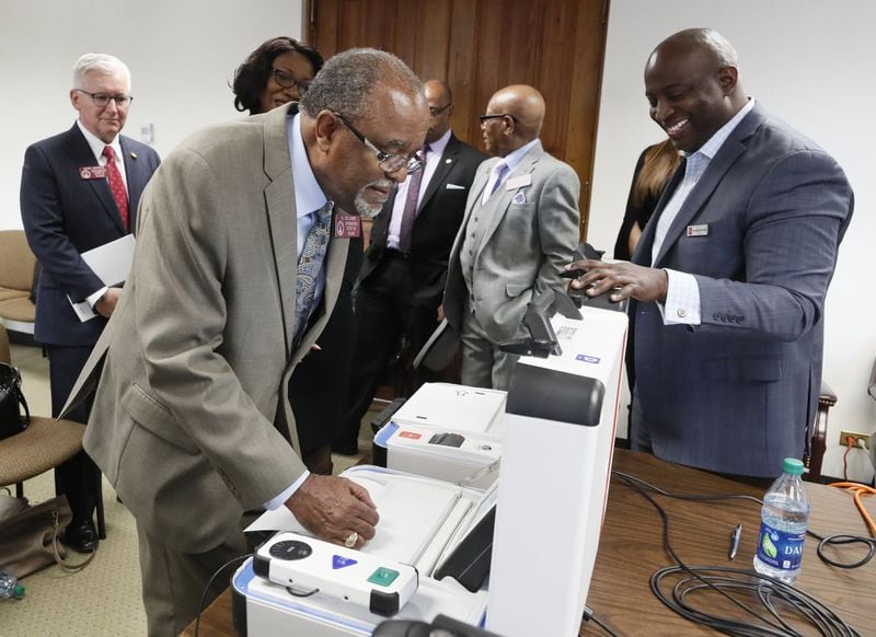 Dwayne Broxton, right, the regional sales director for Hart InterCivic, walks state Rep. Al Williams, D-Midway, through the process of voting during a demonstration of his company’s voting machines to lawmakers. Bob Andres / bandres@ajc.com