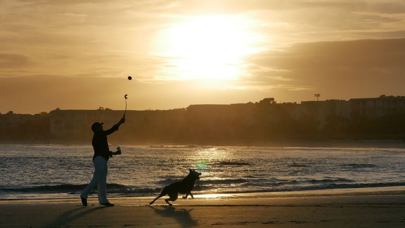 A beachgoer plays with his dog on the beach in St. Simons Island, whose the easygoing seaside lifestyle has drawn many Atlanta retirees. HYOSUB SHIN / HSHIN@AJC.COM