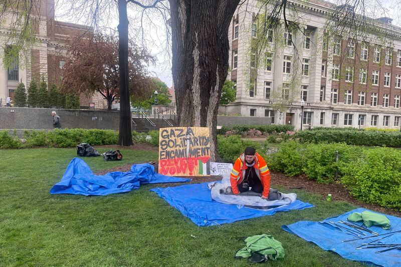 FILE - A graduate student in orange rolls up tents in front of a sign that says "Gaza Solidarity Encampment, Divest Now!" on the University of Minnesota campus in Minneapolis, Thursday, May 2, 2024. Earlier in the day, University of Minnesota officials announced an agreement with protesters to end the encampment on the Minneapolis campus. (AP Photo/Trisha Ahmed, File)