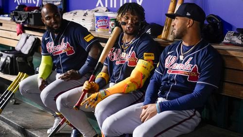 From left, Atlanta Braves' Marcell Ozuna, Ronald Acuña Jr., and Eddie Rosario sit in the dugout during the eighth inning of a baseball game against the Washington Nationals at Nationals Park, Friday, Sept. 22, 2023, in Washington. (AP Photo/Andrew Harnik)