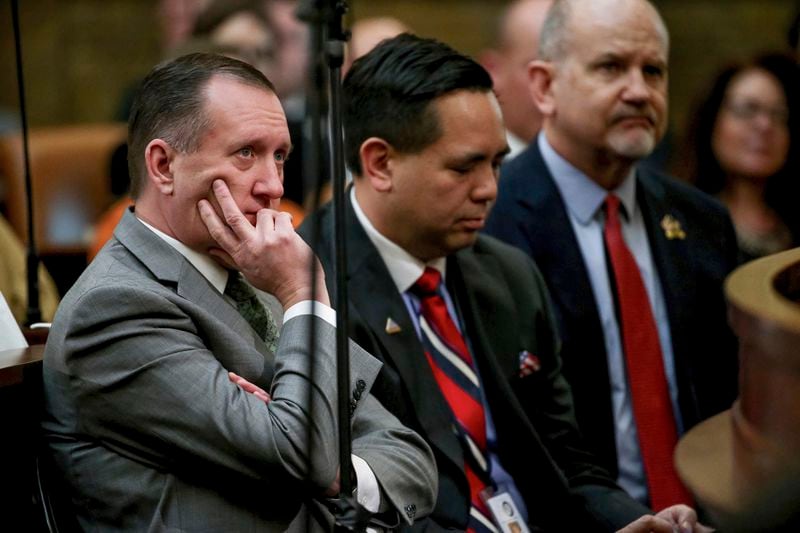 FILE - Utah Auditor John Dougall, left, listens as Gov. Gary Herbert delivers his State of the State address at the Utah State Capitol, on Jan. 30, 2019, in Salt Lake City. Transgender activists have flooded a Utah tip line created to alert state officials to possible violations of a new bathroom law with thousands of hoax reports in an effort to shield trans residents and their allies from any legitimate complaints that could threaten their safety. The onslaught has led the state official tasked by the law with managing the tip line, Dougall, to bemoan getting stuck with the cumbersome task of filtering through fake complaints while also facing backlash for enforcing a law he had no role in passing. (Spenser Heaps/The Deseret News via AP, Pool, File)