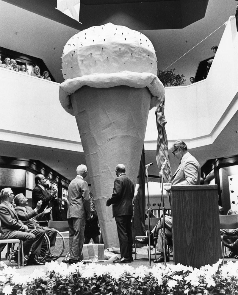 Cone Unveiled. Richard Rich (left), chairman of the board of Rich, Inc. assists Willard G. Rouse, vice chairman of the board of Rouse Co., in unveiling Perimeter Mall's 30-foot papier mache ice cream cone, the symbol of the mall. Jerome S. McDermott (far right), Rouse senior vice president, acted as host for the ribbon-cutting ceremonies celebrating the mall grand opening last week. Photo taken August, 1971. (Mahan Photography/Special)