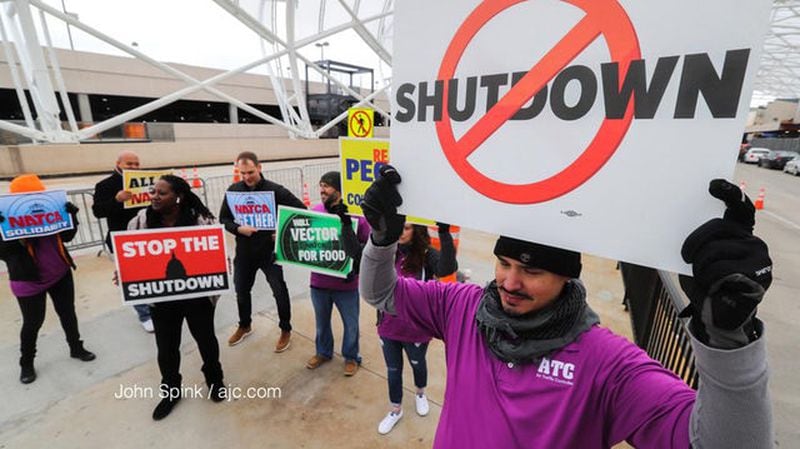 <p>Air traffic controller Rafael Naveira and fellow ATC workers protest the federal shutdown at the north terminal. Photo: JOHN SPINK / AJC<br /> &nbsp;</p>