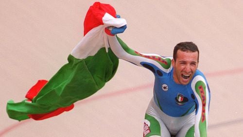 Andrea Collinelli carries the Italian flag after winning the men's individual pursuit in the cycling competitions Thursday, July 25, 1996, at the Stone Mountain Velodrome. (Rich Addicks/AJC)
