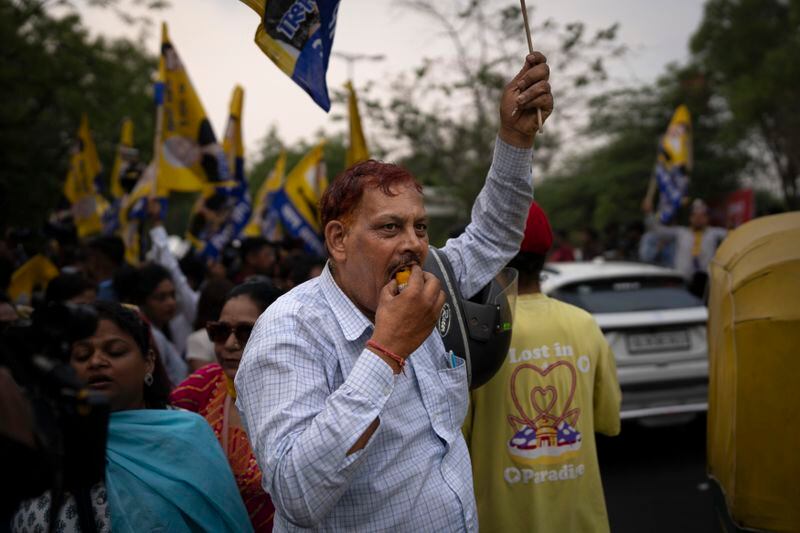 A supporter of the Aam Aadmi Party eats a sweet as he waits with others for the release of the party leader Arvind Kejriwal from Tihar Jail in New Delhi, India, Friday, May 10, 2024. The Supreme Court ordered Arvind Kejriwal's temporary release enabling him to campaign in the country's national election until the voting ends on June 1. (AP Photo/Altaf Qadri)